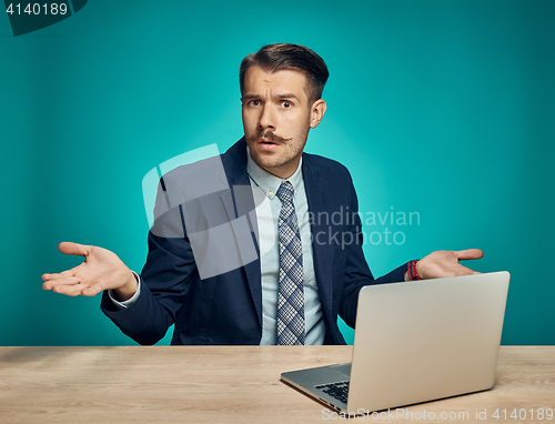 Image of Sad Young Man Working On Laptop At Desk