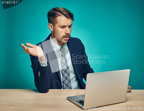 Image of Sad Young Man Working On Laptop At Desk