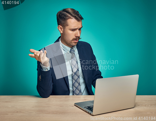 Image of Sad Young Man Working On Laptop At Desk