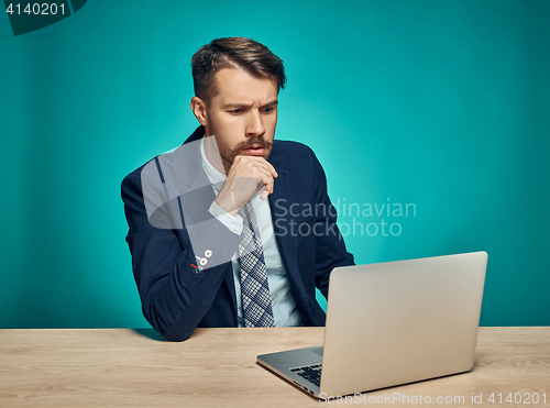 Image of Sad Young Man Working On Laptop At Desk