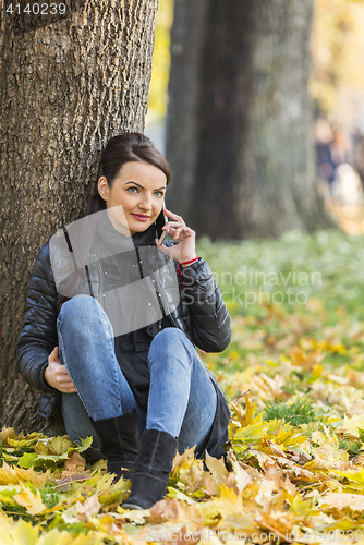 Image of Woman with a Mobile in a Forest in the Autumn