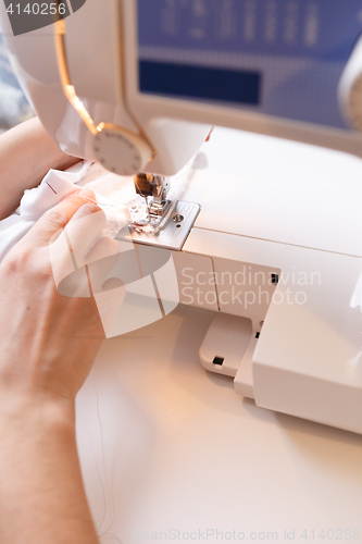 Image of Woman sewing white cloth close-up