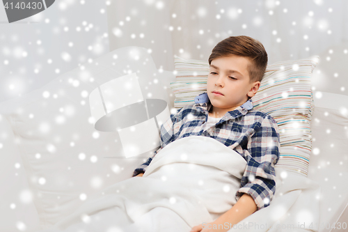 Image of ill boy with flu lying in bed at home