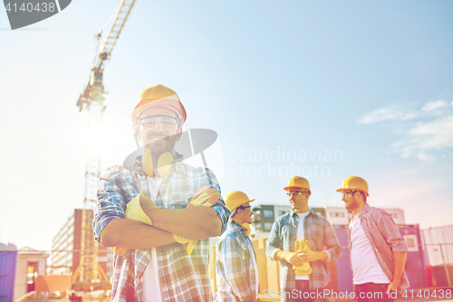 Image of group of smiling builders in hardhats outdoors