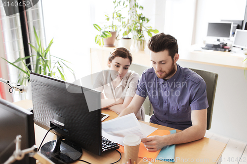 Image of creative team with computer and papers in office
