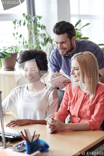 Image of happy creative team with computer in office