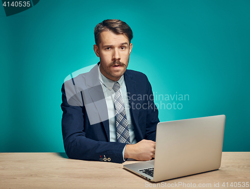 Image of Sad Young Man Working On Laptop At Desk