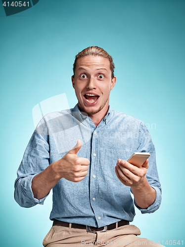 Image of The young smiling caucasian man on blue background