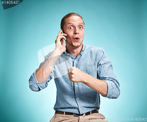 Image of The young smiling caucasian man on blue background