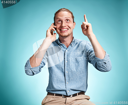 Image of The young smiling caucasian man on blue background