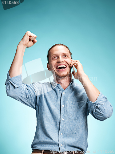 Image of The young smiling caucasian man on blue background