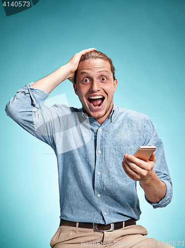 Image of The young smiling caucasian man on blue background