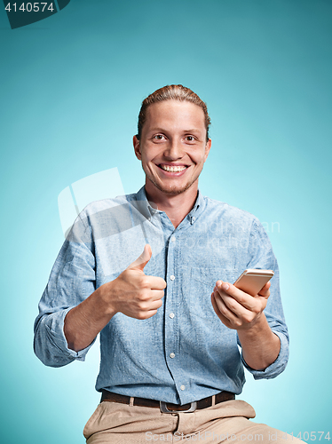 Image of The young smiling caucasian man on blue background