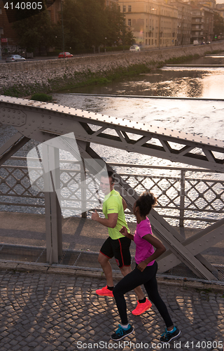Image of young multiethnic couple jogging in the city