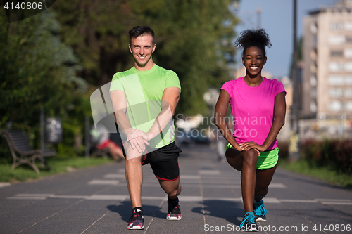 Image of jogging couple warming up and stretching in the city