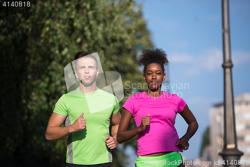 Image of young smiling multiethnic couple jogging in the city