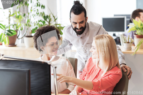 Image of happy creative team with computer in office