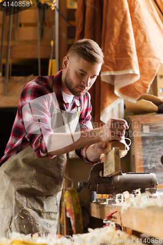 Image of carpenter working with plane and wood at workshop