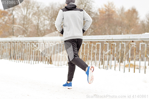 Image of man running along snow covered winter bridge road