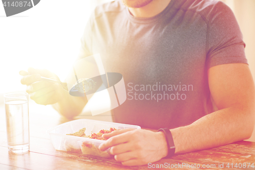 Image of close up of man with fork and water eating food