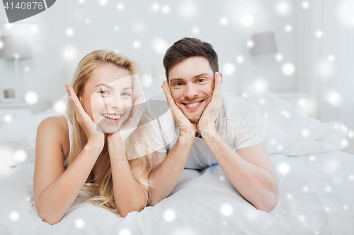 Image of happy couple lying in bed at home