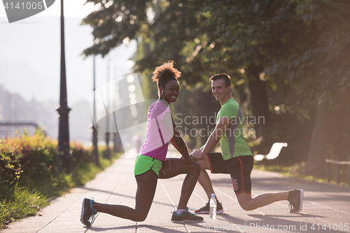 Image of jogging couple warming up and stretching in the city