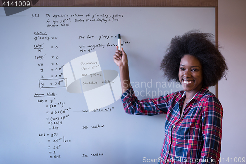 Image of African American woman writing on a chalkboard in a modern offic