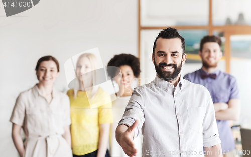 Image of happy man making handshake over office team