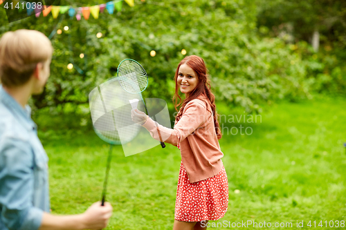 Image of happy friends playing badminton at summer garden