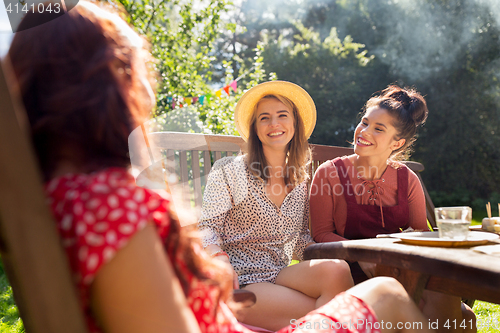 Image of happy friends having dinner at summer garden