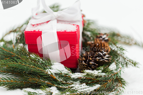 Image of christmas gift and fir wreath with cones on snow