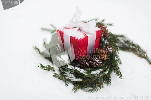 Image of christmas gift and fir wreath with cones on snow