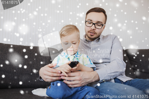 Image of father and son with remote watching tv at home