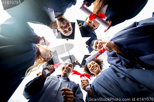 Image of happy students or bachelors with diplomas