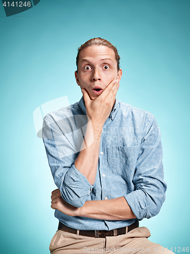 Image of The surprised young man over blue background