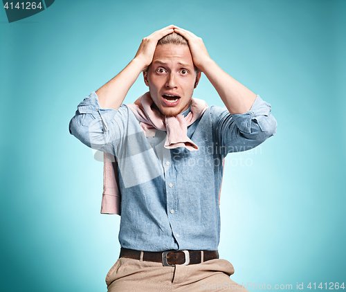 Image of The surprised young man over blue background