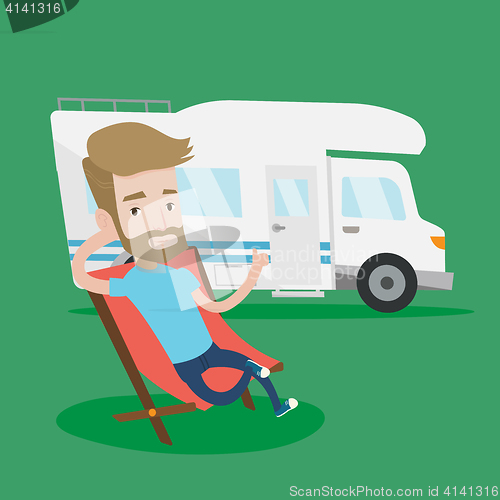 Image of Man sitting in chair in front of camper van.