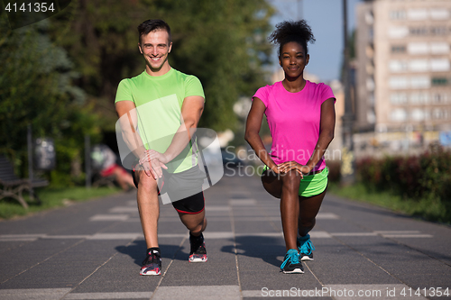 Image of jogging couple warming up and stretching in the city