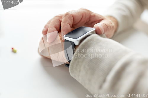 Image of close up of old man hand with pill and smart watch