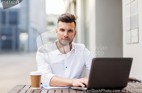 Image of man with laptop and coffee at city cafe