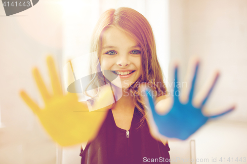 Image of happy girl showing painted hand palms at home