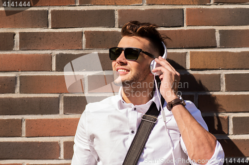 Image of young man in headphones over brickwall