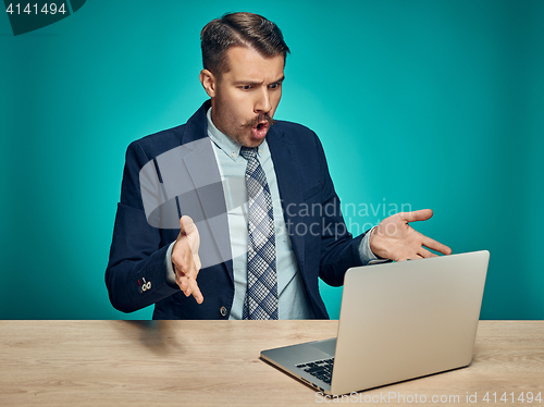 Image of Sad Young Man Working On Laptop At Desk