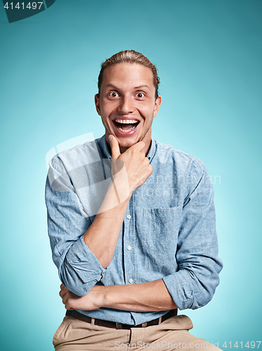 Image of Happy excite young man smiling over blue background