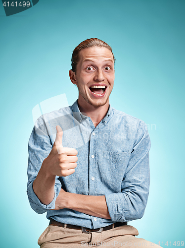 Image of Happy excite young man smiling over blue background