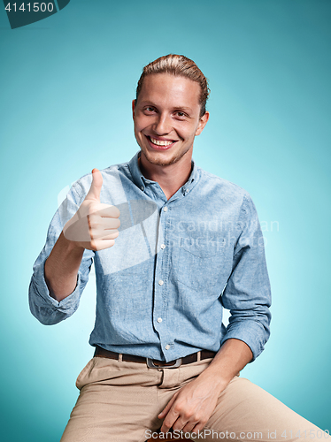 Image of Happy excite young man smiling over blue background