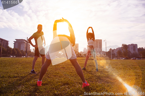 Image of multiethnic group of people stretching in city park
