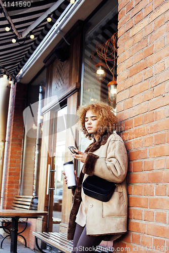 Image of young pretty african american women drinking coffee outside in c