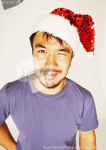 Image of funy exotical asian Santa claus in new years red hat smiling