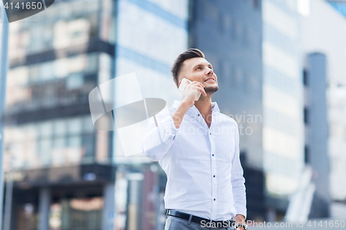 Image of happy man with smartphone calling on city street